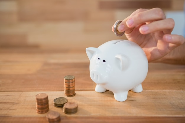 Hand inserting coin in piggy bank