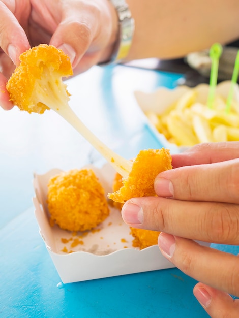 Hand is holding a stretch cheese ball ready to be eaten 