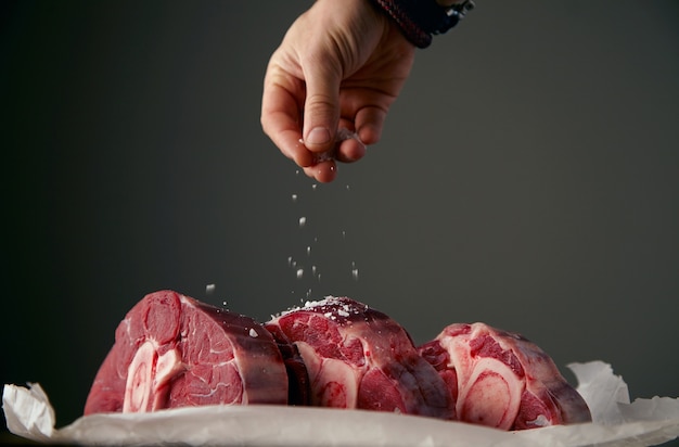 La mano sta satling tre bistecche di carne fresca con l'osso