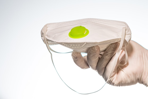 Hand in a latex glove holding a facemask with filter isolated on white