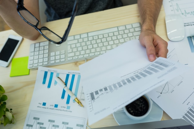 Hand of male graphic designer holding graph document