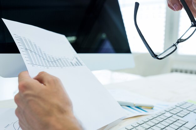 Hand of male graphic designer holding graph document