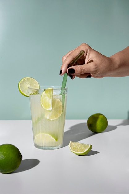 Hand mixing caipirinha cocktail with straw