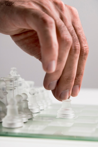Free photo hand moving transparent chess pieces