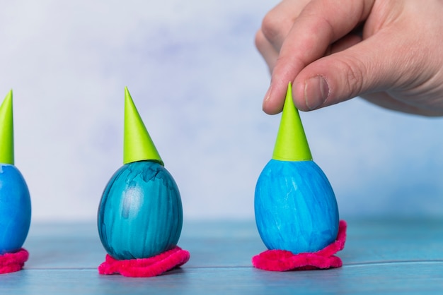 Free photo hand near set of easter eggs with decorative party hats