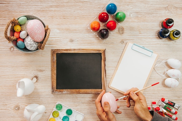 Hand painting egg at table with blackboard