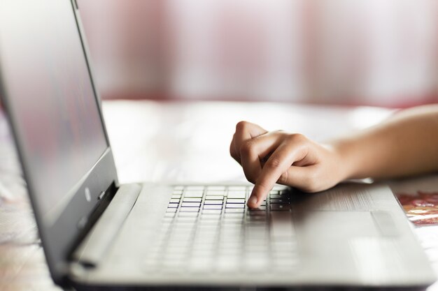 Hand of a person typing on a laptop with a blurry