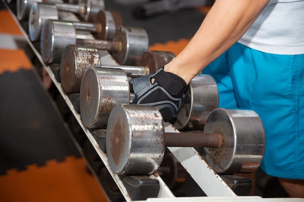 Free photo hand picking up old dumbbell on the rack