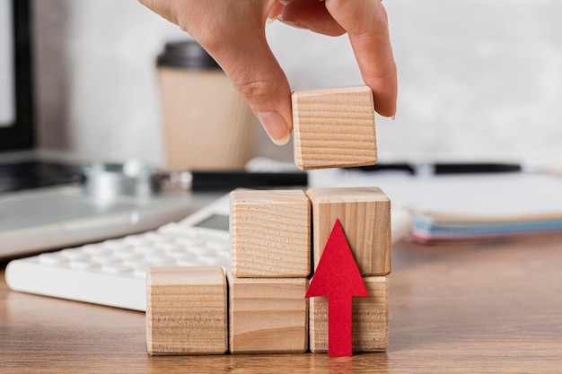 Free photo hand placing wooden block to represent growth