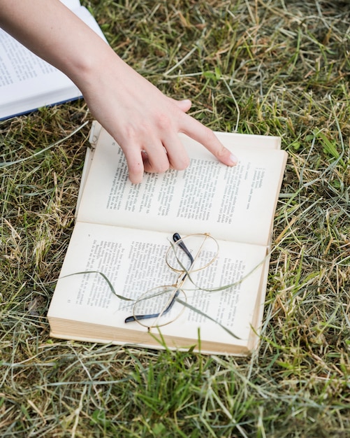 Hand pointing at open book on grass