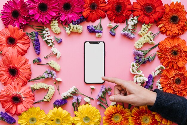 Hand pointing at smartphone in flowers