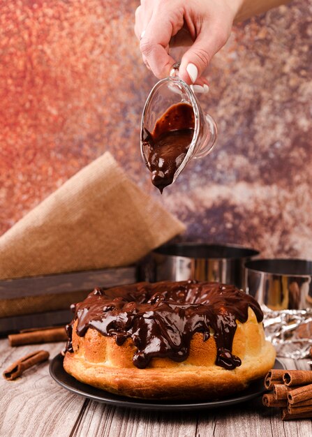 Hand pouring chocolate topping on cake