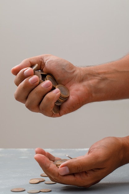 Free photo hand pouring coins into another one.