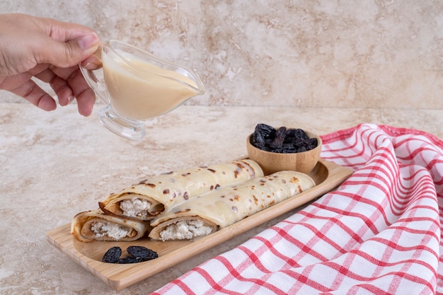 Hand pouring condensed milk on homemade crepes.High quality photo