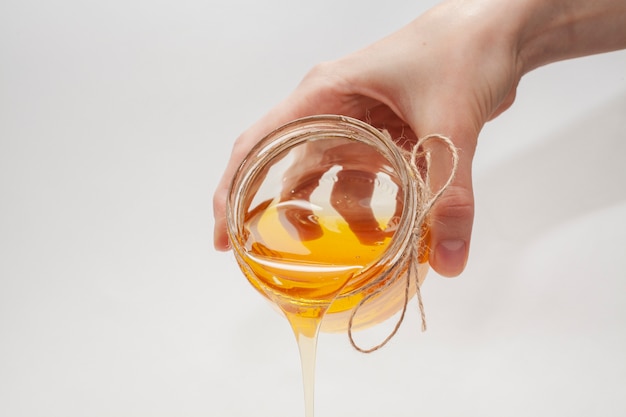 Hand pouring honey from a jar