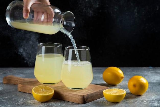 유리 컵에 레몬 주스를 붓는 손.
