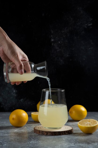 유리 컵에 레몬 주스를 붓는 손.