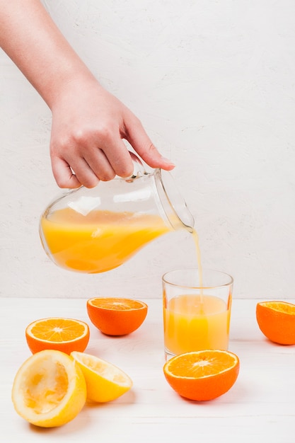 Рука наливая апельсиновый сок в стакан
