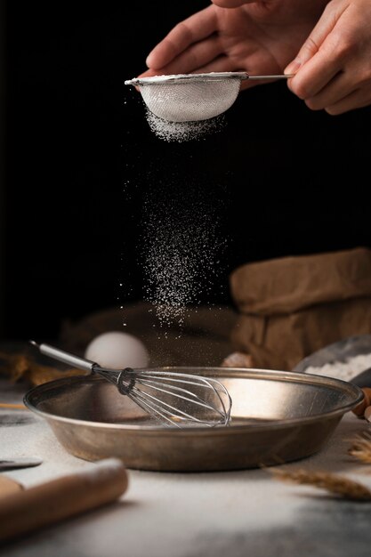 Hand pouring sugar into cooking pan