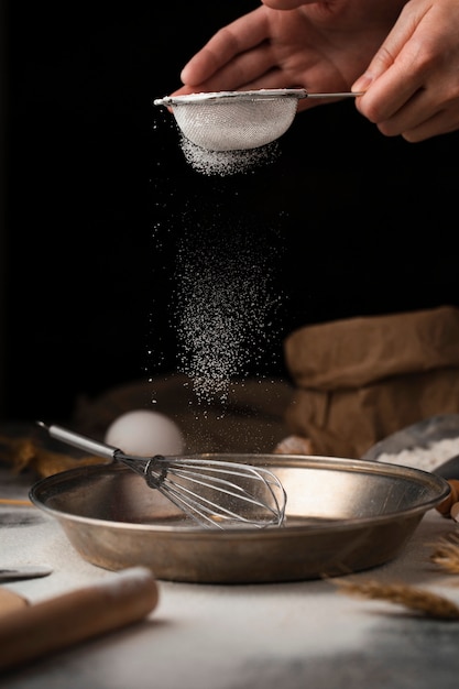 Hand pouring sugar into cooking pan