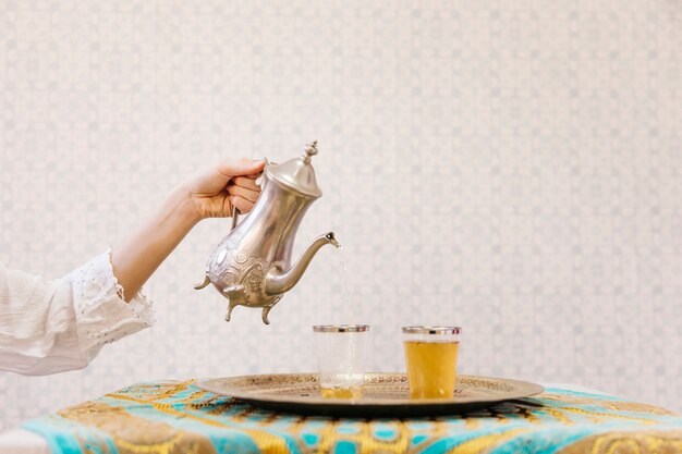 Hand pouring tea into glass