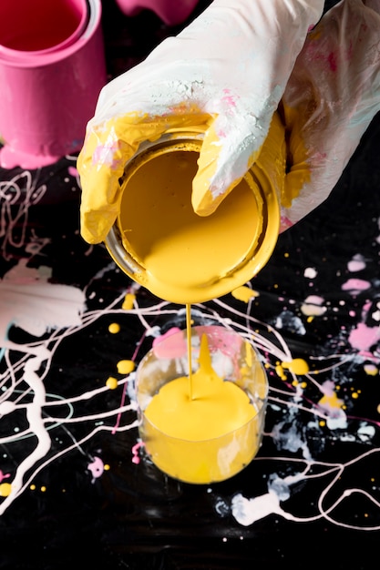 Hand pouring yellow paint from can