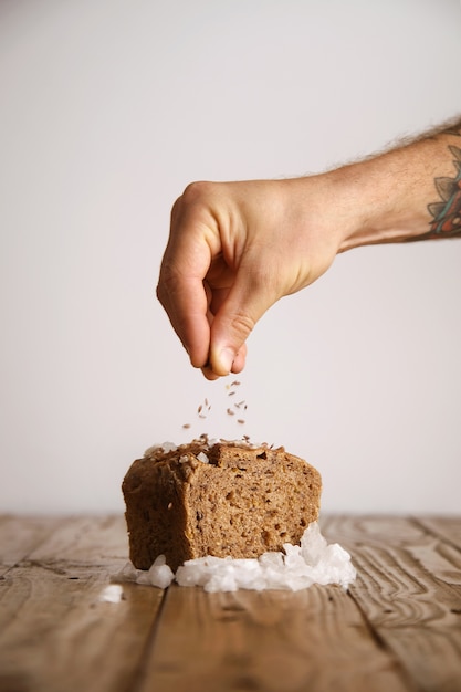 Hand pours lavender seeds on rye bread with sea salt organically baked in artisan bakery