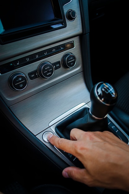 Hand pressing a button next to gear stick