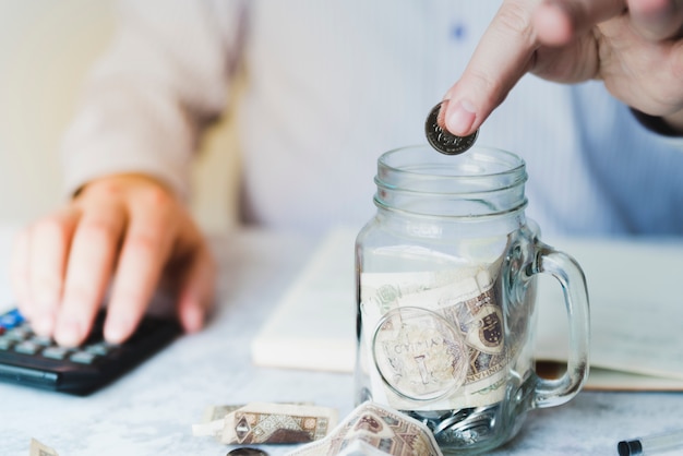 Free photo hand putting coin inside jar