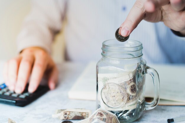 Hand putting coin inside jar