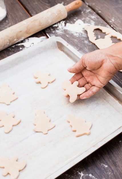 Hand putting man shaped pastry on baking sheet