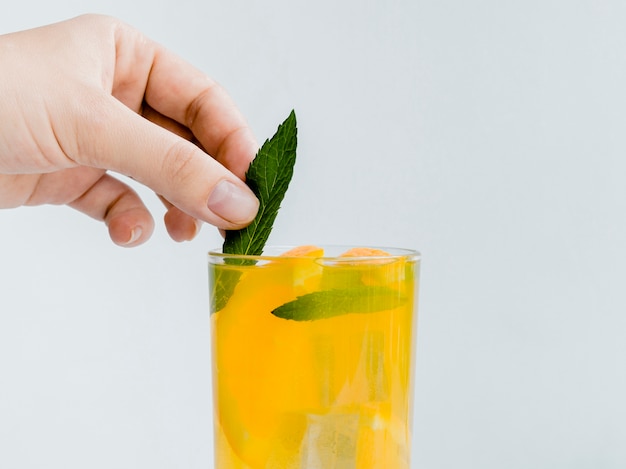 Hand putting mint in bright cold tasty drink