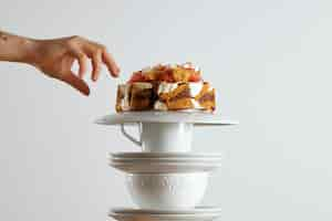 Free photo a hand reaching out to grab a piece of beautiful light brown sponge cake with chocolate and cream and grapefruit