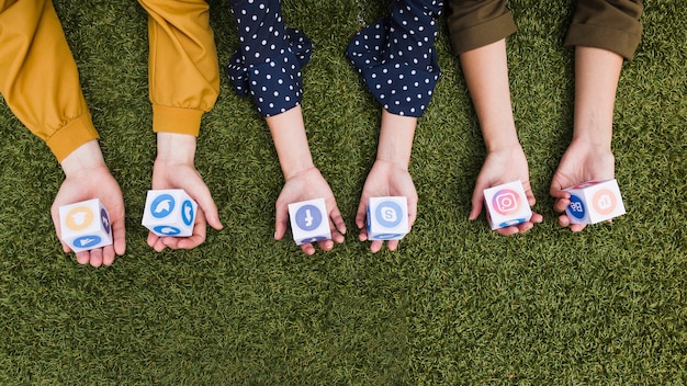 Hand's holding social media app icons blocks on green grass