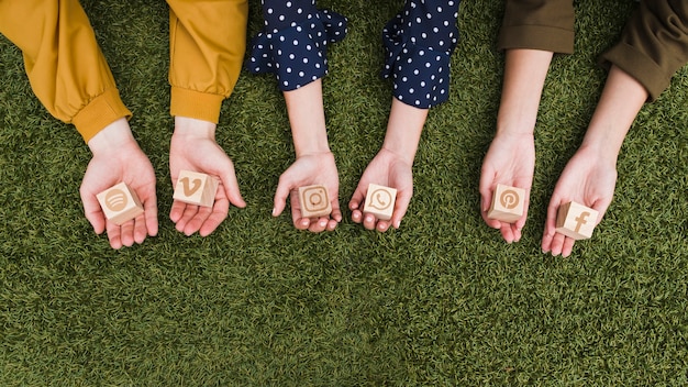 hand's holding social media app icons wooden blocks on green grass