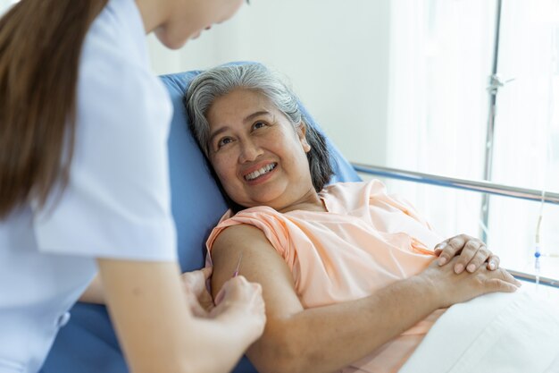 웃 고, 복사 공간, 건강 및 의료 개념으로 침대에 누워 노인 여성 환자에 주입하기 위해 손을 잡고 간호사 알약