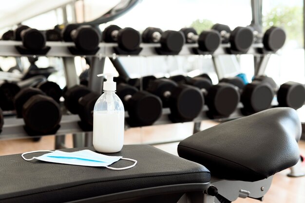 hand sanitizer and medical mask on gym bench