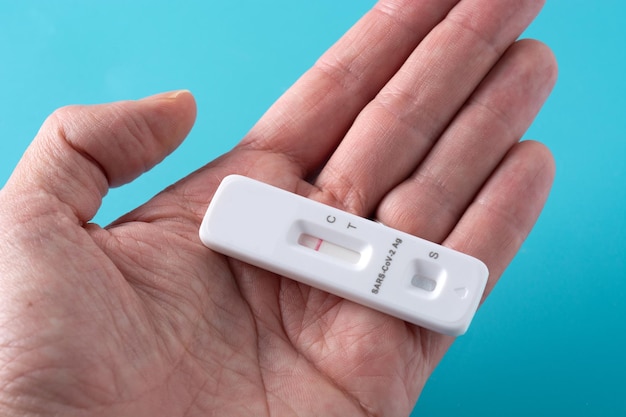 Hand showing Covid-19 rapid antigen test on blue background