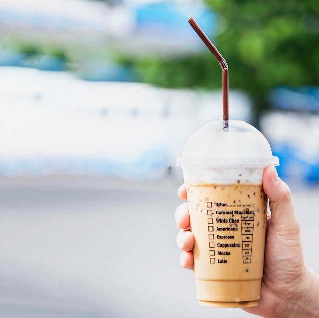 Free photo hand showing fresh ice coffee cup, refreshment with ice coffee cup