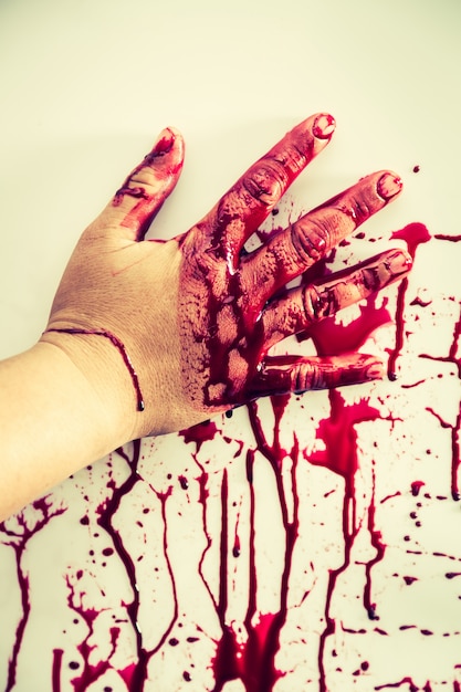 Hand stained with blood touching a wall