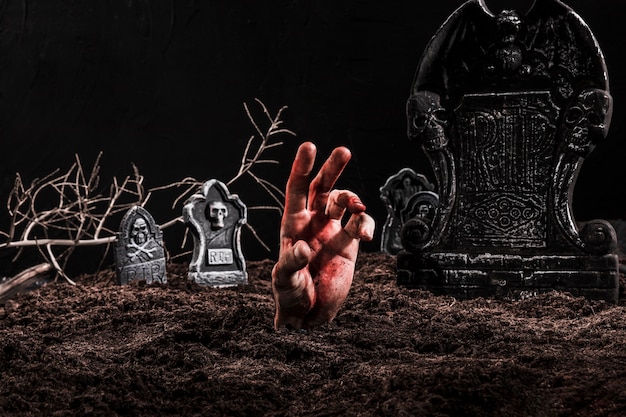 Hand sticking out grave on dark cemetery