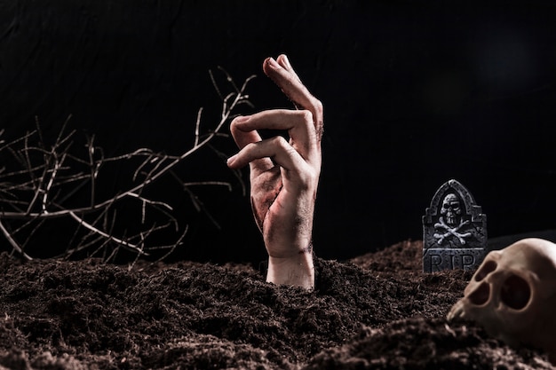 Free photo hand sticking out of ground near skull