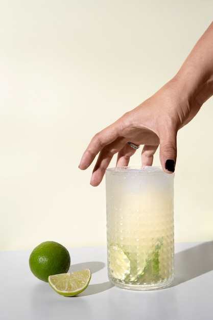 Hand taking caipirinha cocktail glass