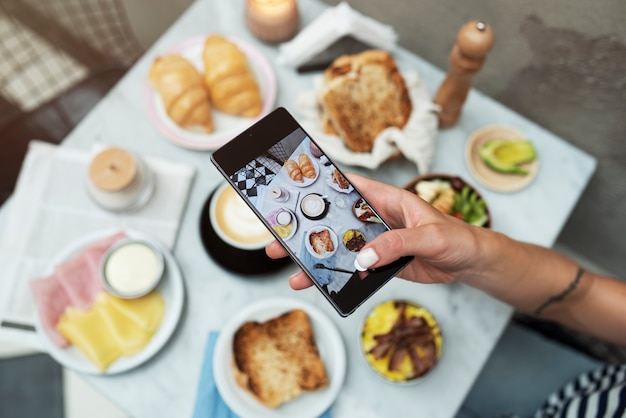 Foto gratuita mano che scatta foto di cibo delizioso da vicino