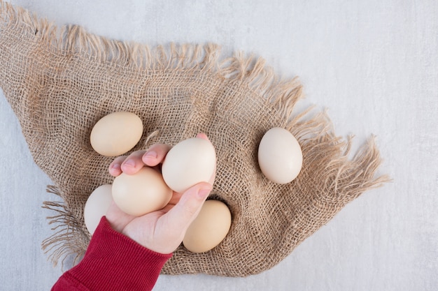 대리석 테이블에 헝겊 조각에 번들에서 계란을 가져가는 손.