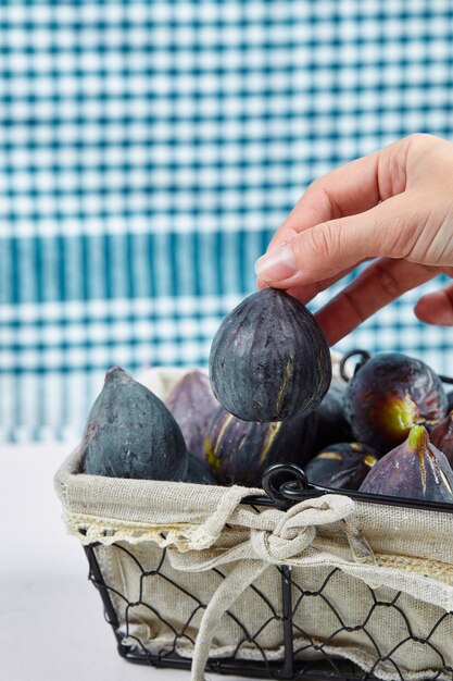 Hand taking a fig from the basket.