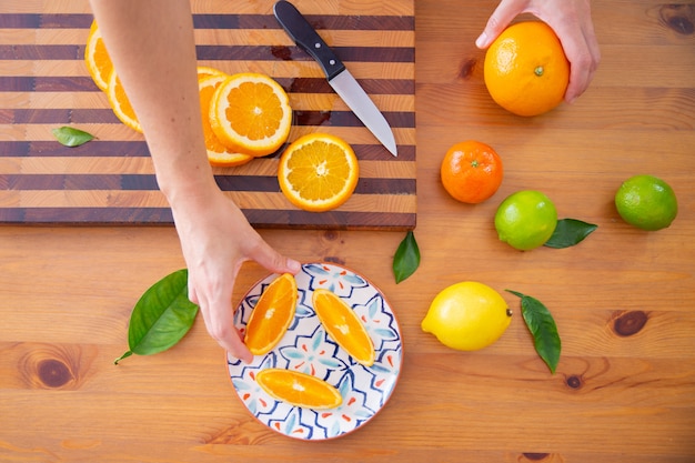 Рука берет кусок апельсина из керамической тарелки