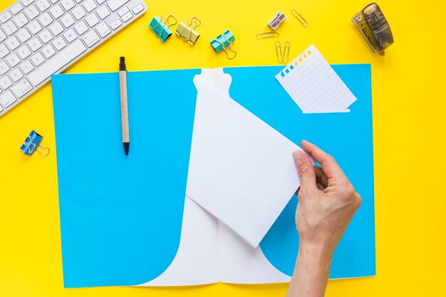 Hand taking paper from folder on desktop