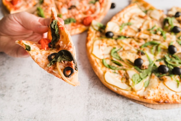 Hand taking pizza slice