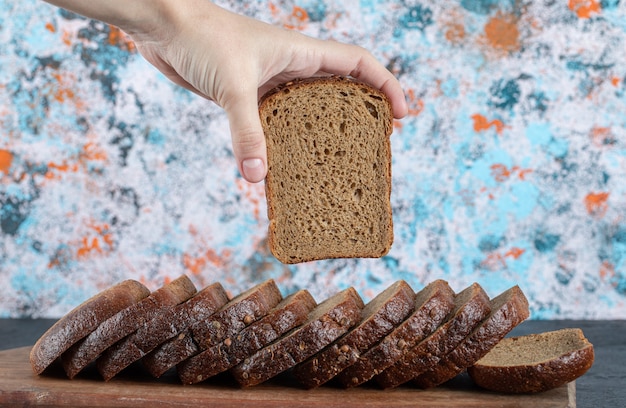 Mano che cattura una fetta di pane fresco sulla tavola di legno.